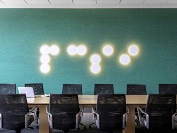 A green wall with dotted lights that spell PCSI in brail