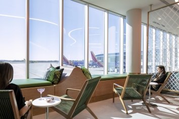 People seated in green chairs facing windows and Southwest Airlines planes