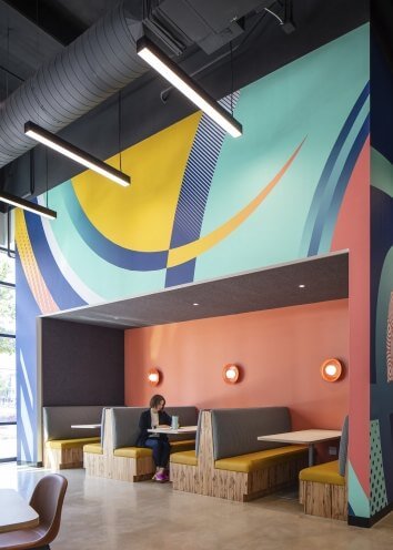 Colorful wall with a woman sitting in a booth beneath it