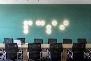 A green wall with dotted lights that spell PCSI in brail