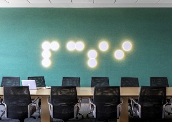 A green wall with dotted lights that spell PCSI in brail
