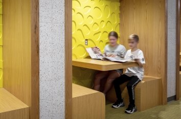 Two students read in a yellow, wooden booth